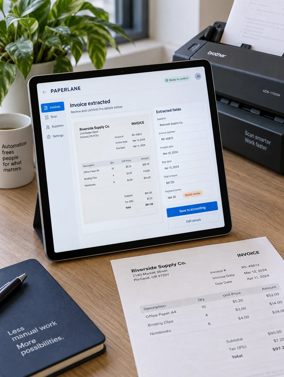 Tablet standing beside a real invoice and compact document scanner