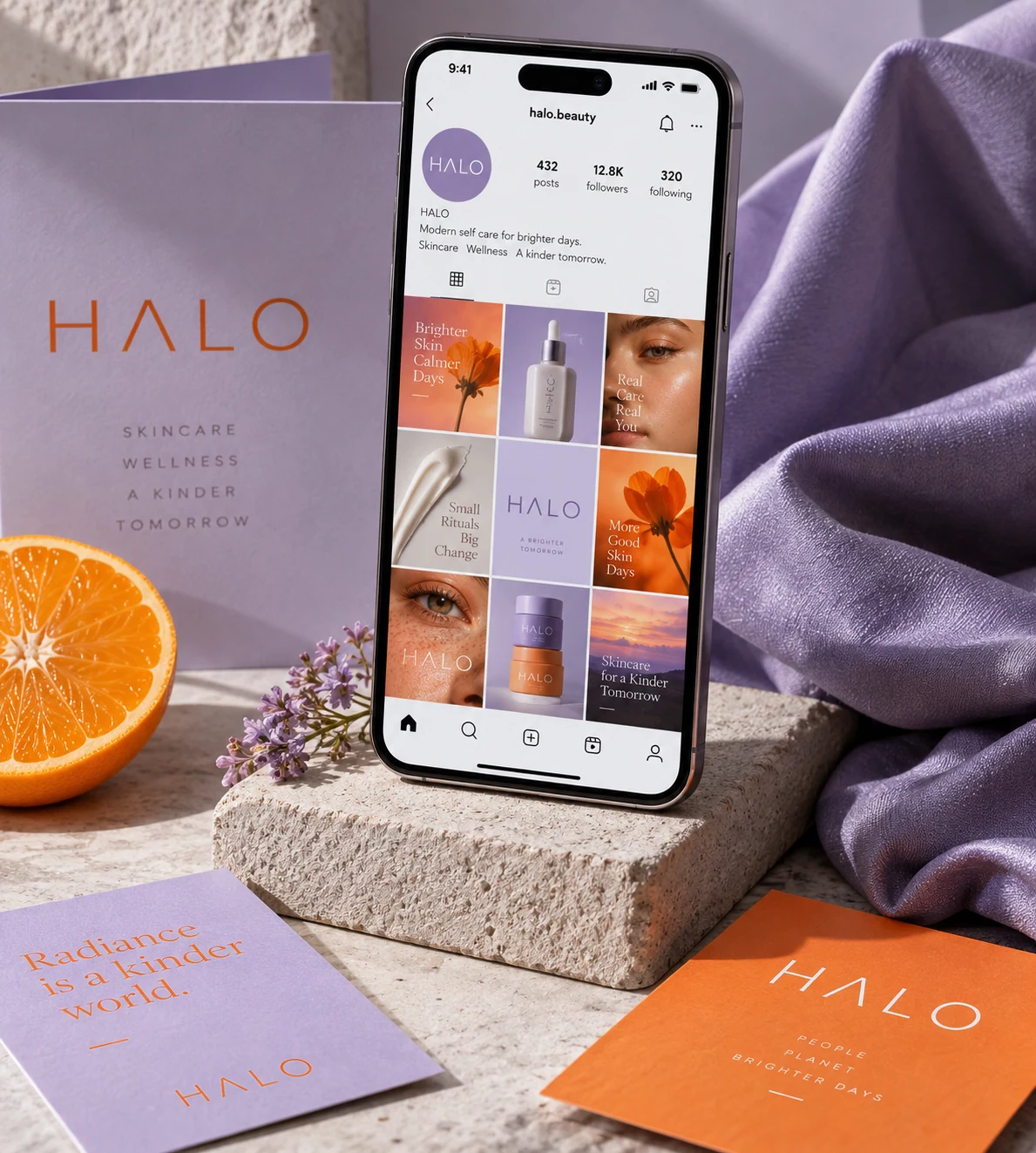 A smartphone standing on a small sculptural block beside fabric and branded cards, showing a refined social campaign for fictional beauty brand HALO