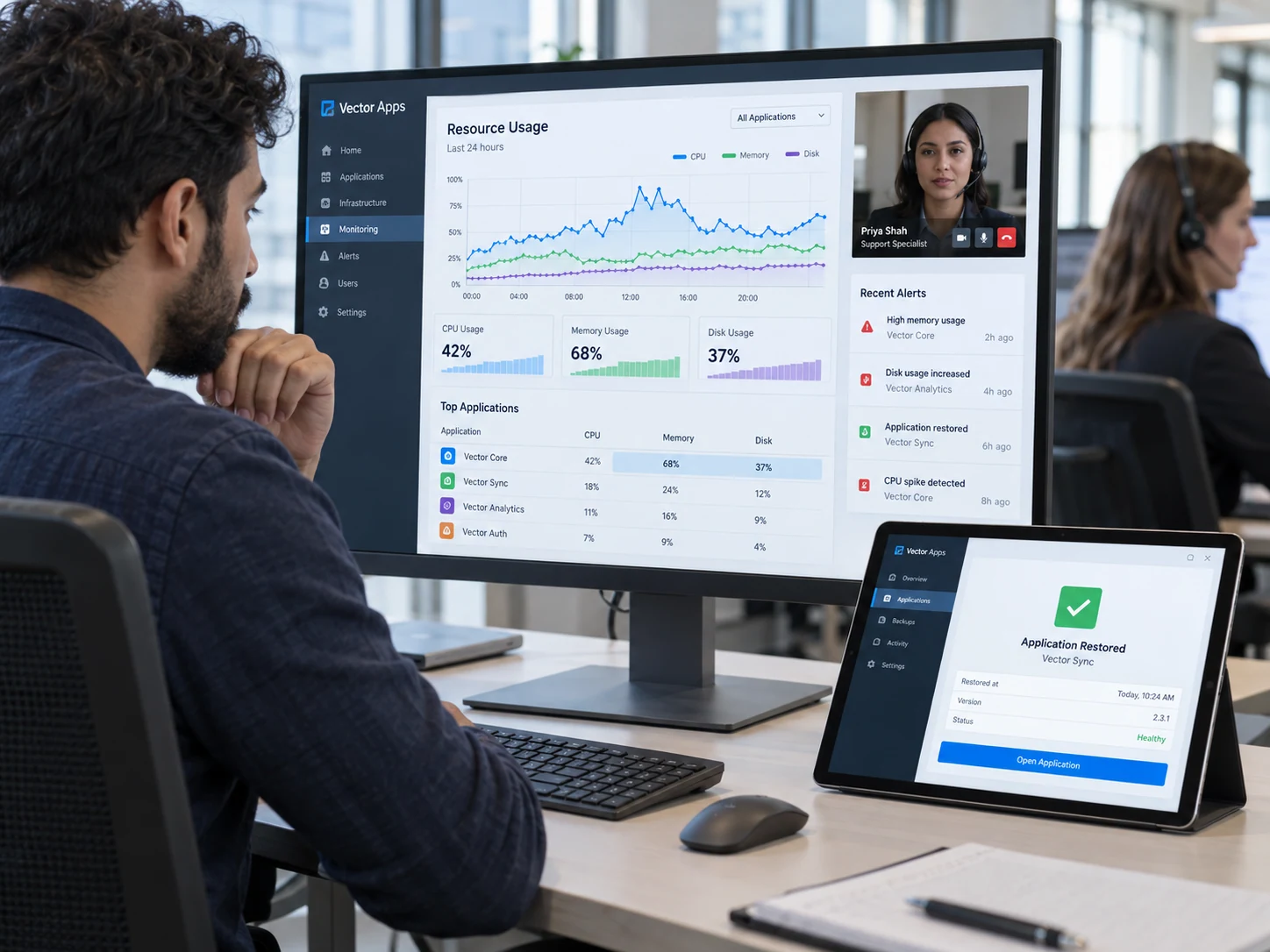 Cloud support specialist at large monitor investigates a clear resource trend for fictional 'Vector Apps', tablet beside shows restored application