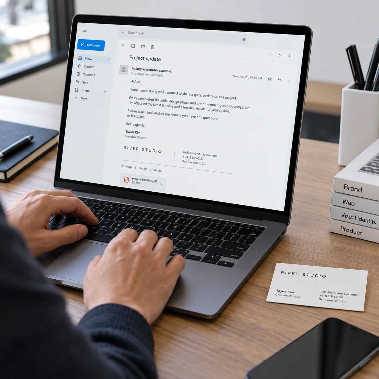 Laptop on small agency desk shows a composed professional email from 'hello@riverstudio.example' with consistent company signature and simple subject 'Project update'